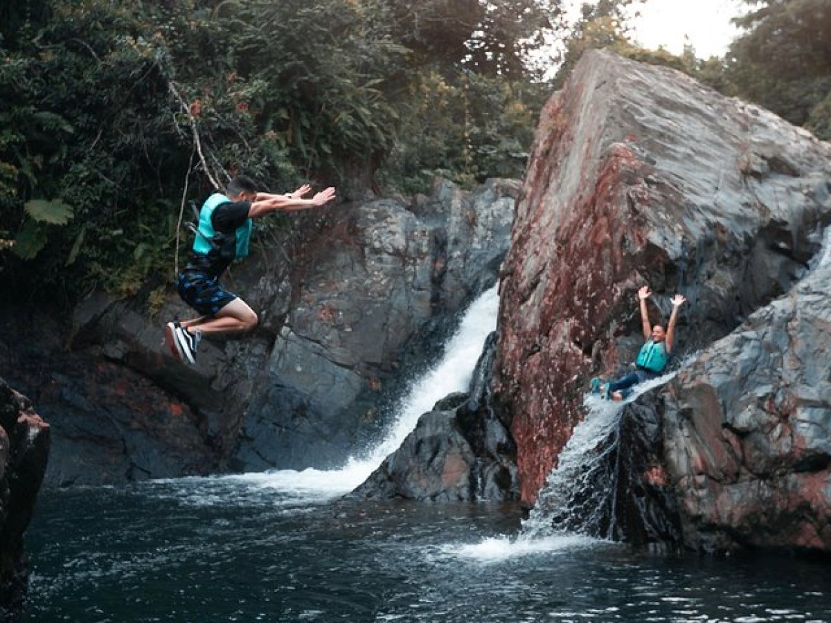 a group of people on a rock next to a waterfall