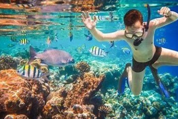 man snorkeling in clear water