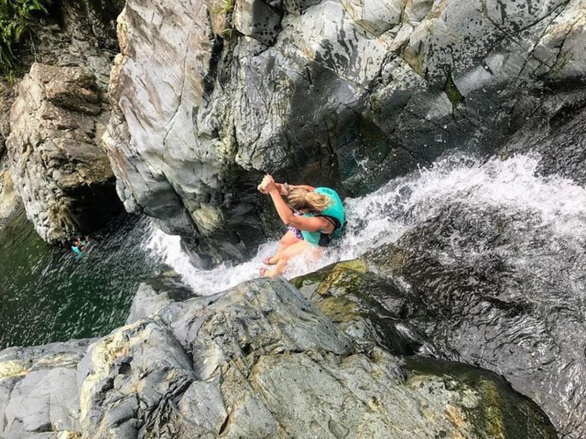 a man swimming in water next to the rock