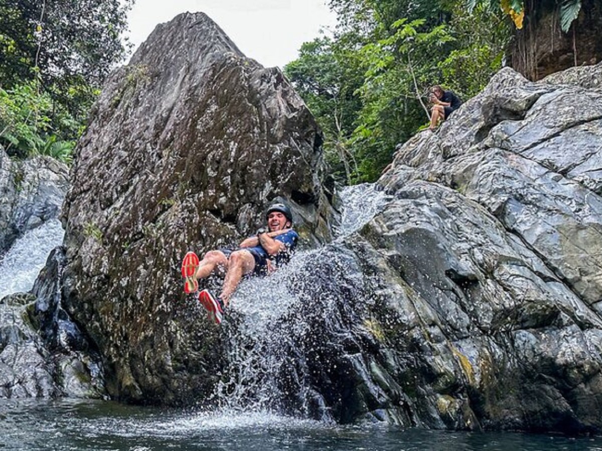 a man swimming in water next to the rock