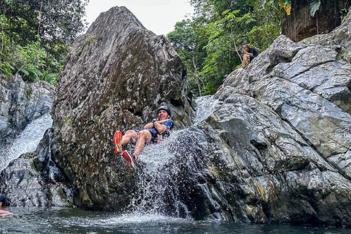 a man swimming in water next to the rock