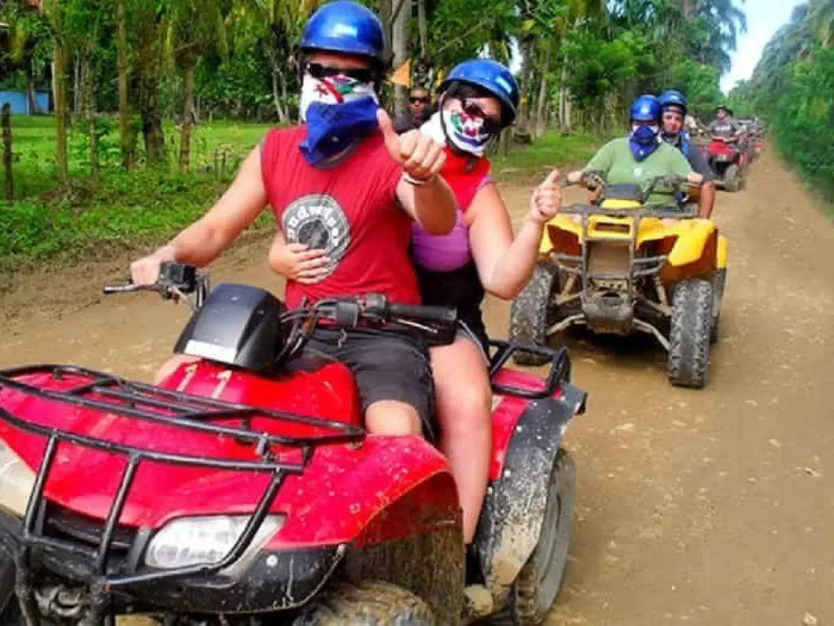 a boy wearing a helmet riding a motorcycle down a dirt road