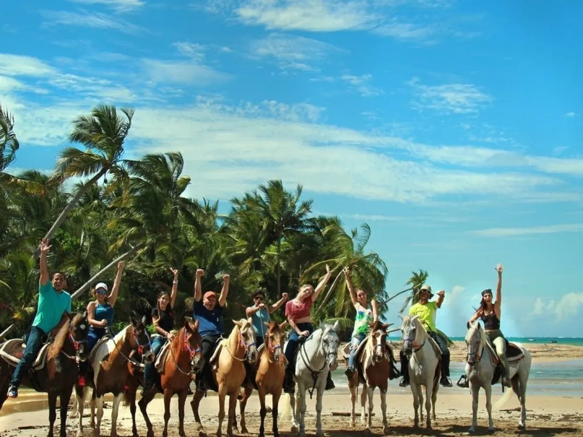 a group of people riding a horse on a beach