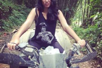 a woman riding a bike down a dirt road