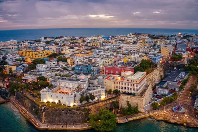 Aerial view of a colorful coastal cityscape with historic buildings and ocean.