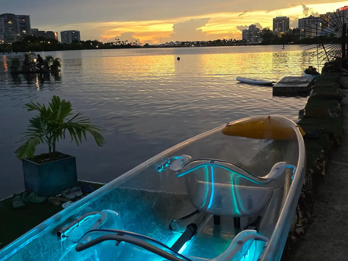 Clear kayak with blue lights on a lakeside at sunset.