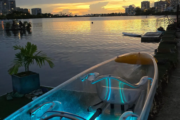Clear kayak with blue lights on a lakeside at sunset.