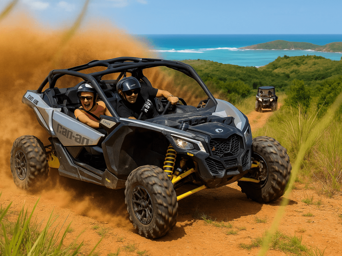 Two people in an ATV driving on a dirt trail with ocean in the background.