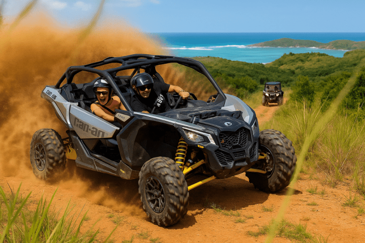 Two people in an ATV driving on a dirt trail with ocean in the background.