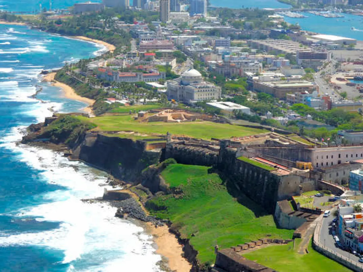 Aerial view of a coastal city with a historic fort and ocean waves.