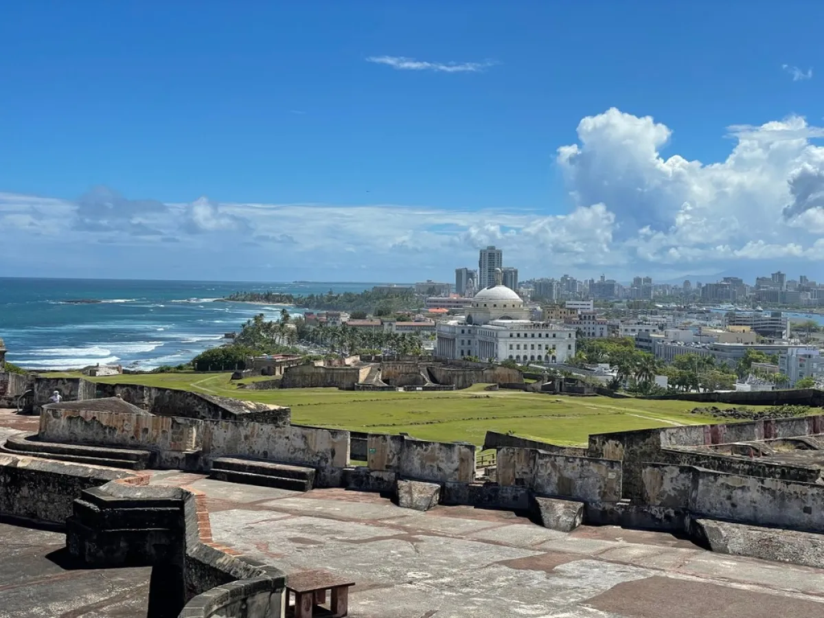 Historic fortress with ocean view, city skyline, and blue sky.