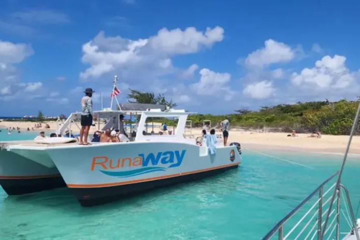 Boat named 'Runaway' by a sandy beach with people and clear blue water under a partly cloudy sky.