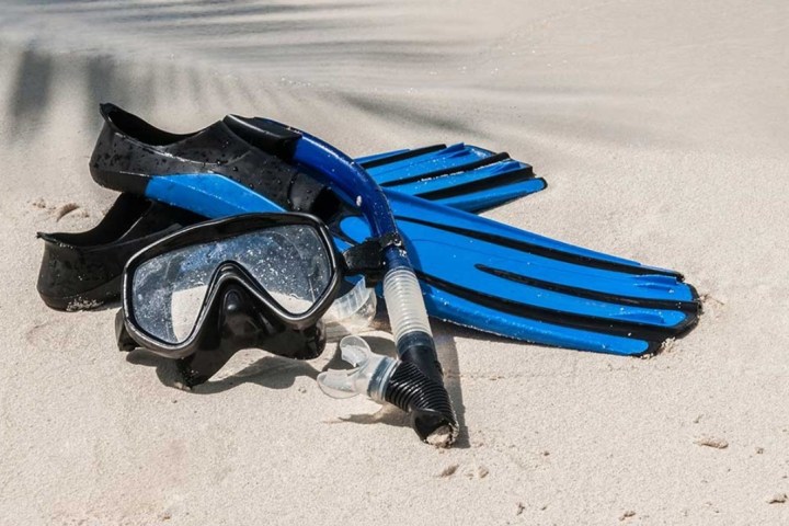 Snorkel gear with fins, mask, and snorkel tube on sandy beach.