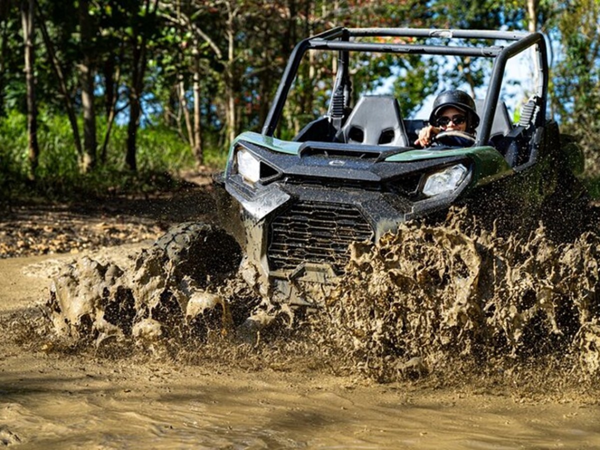 Off-road vehicle driving through muddy water in a forest.