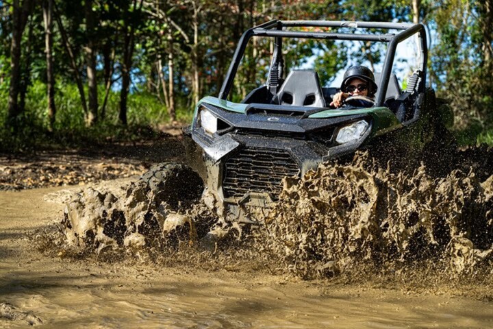 Off-road vehicle driving through muddy water in a forest.