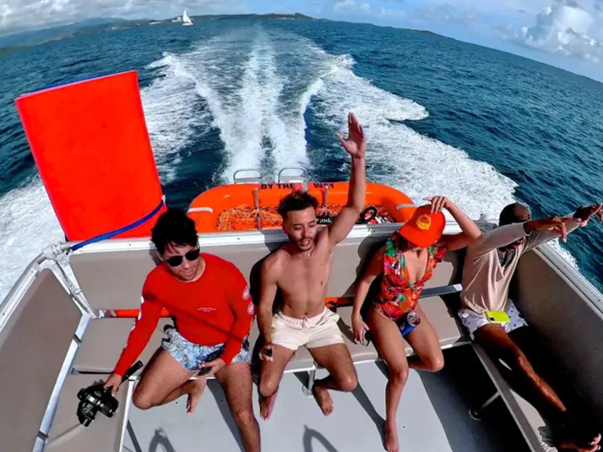 Four people enjoying a speedboat ride on open ocean water under a clear blue sky.