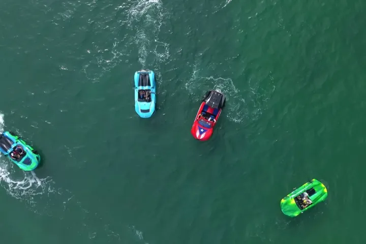 Four colorful jet skis on green water, viewed from above.