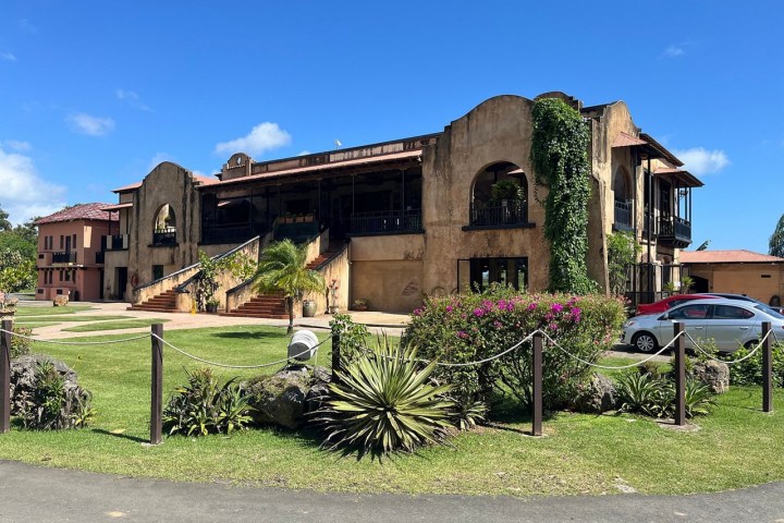 Rustic building with arched windows, surrounded by greenery under a clear blue sky.