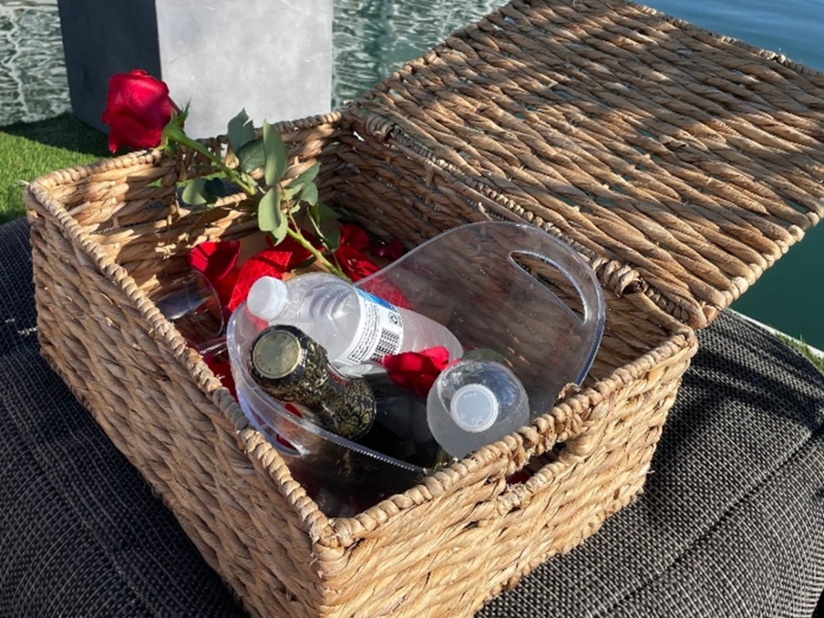 Wicker basket with plastic bottles and roses by the water.