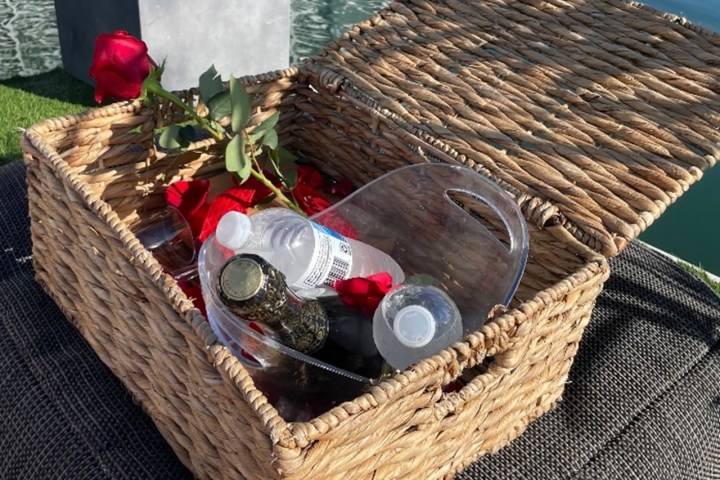 Wicker basket with plastic bottles and roses by the water.