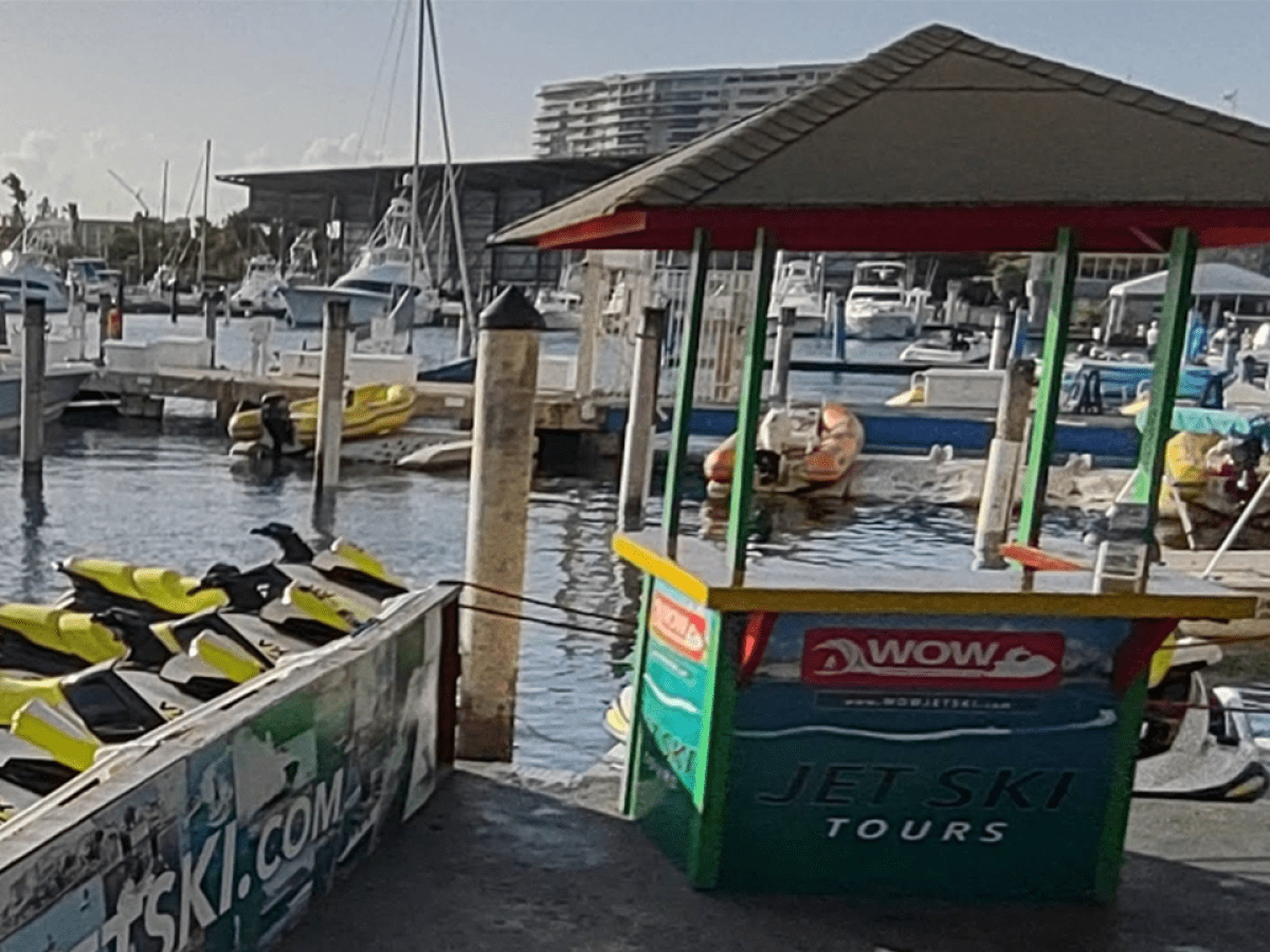 Jet ski rental booth at a marina with several docked boats.