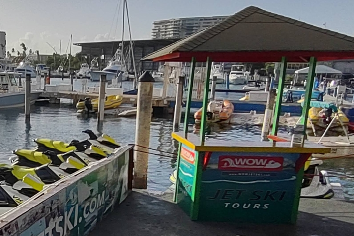 Jet ski rental booth at a marina with several docked boats.