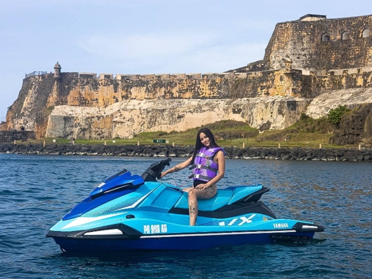 Person on a blue jet ski near a historic fortress by the sea.
