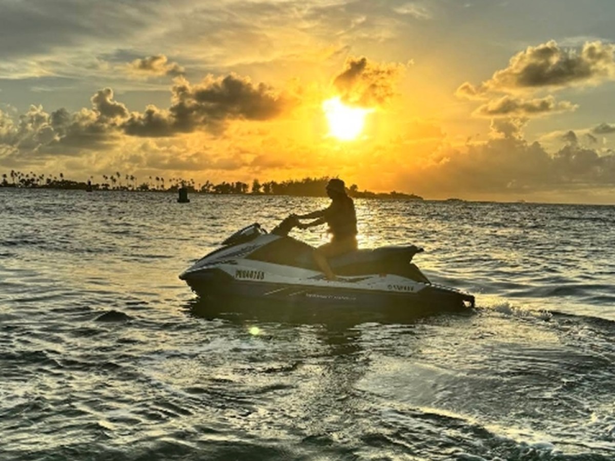 Person on a jet ski at sunset over the ocean.