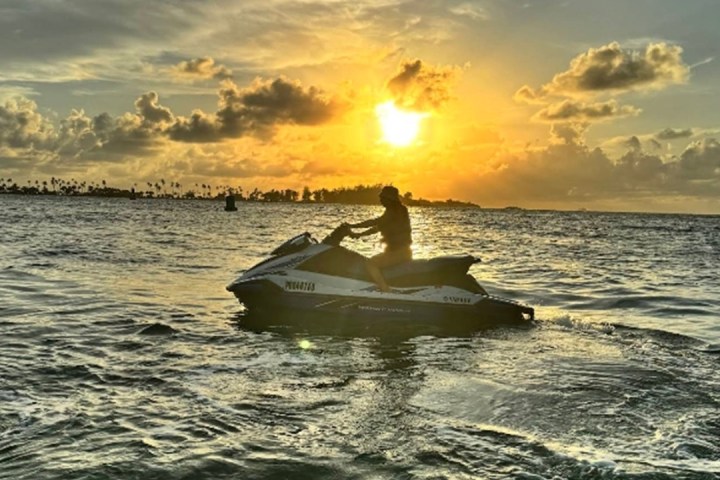 Person on a jet ski at sunset over the ocean.
