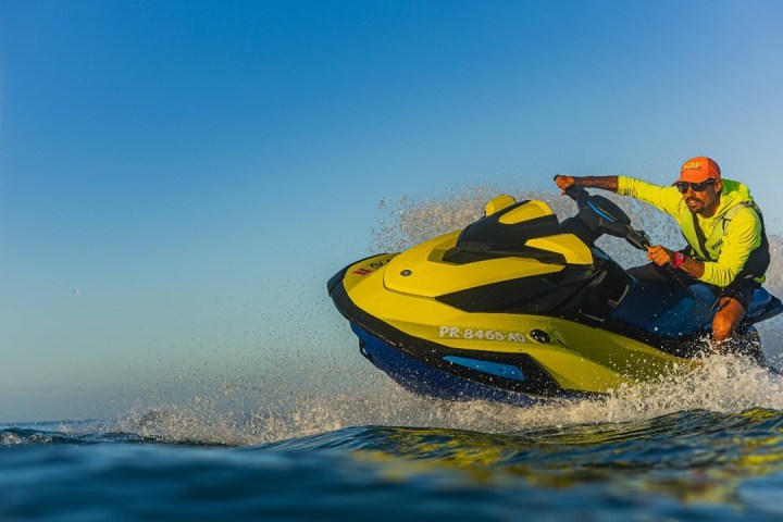 Person riding a yellow jet ski on the water with a clear blue sky.