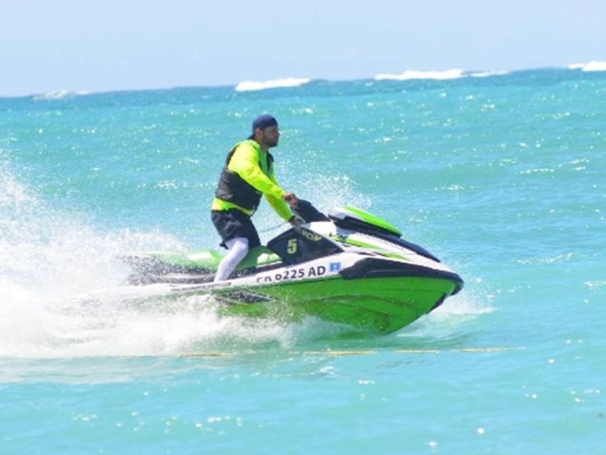 Person in neon shirt riding a green jet ski on the ocean.