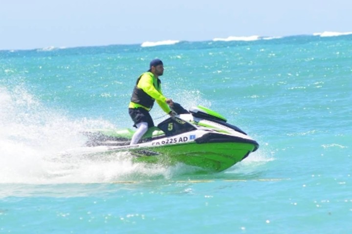 Person in neon shirt riding a green jet ski on the ocean.