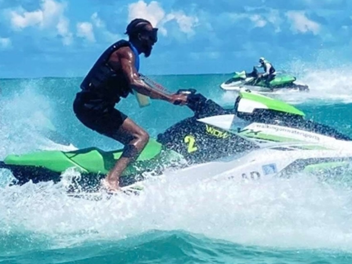 Three people riding jet skis in turquoise ocean under blue sky.