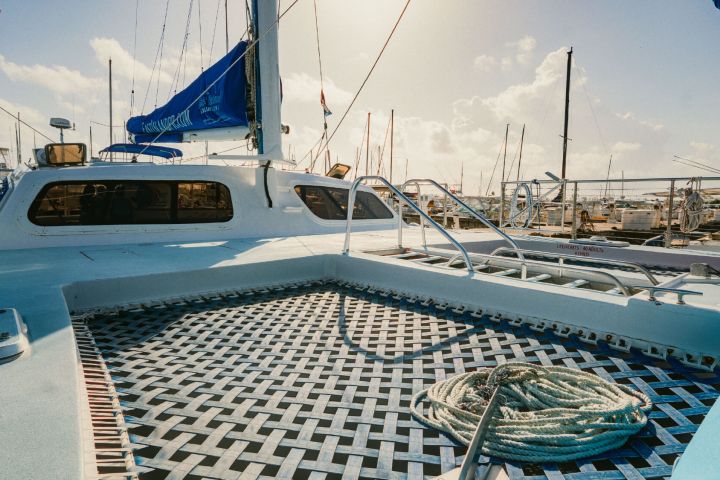 Catamaran deck with netting, coiled rope, and marina view.