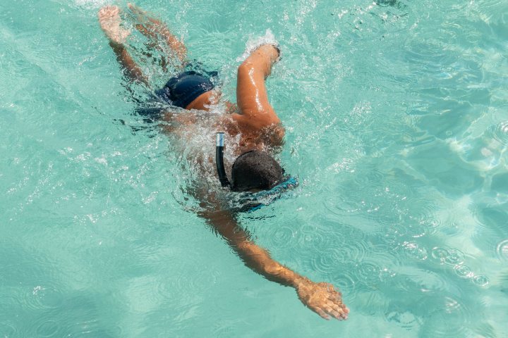 Person swimming freestyle in a pool with blue water.