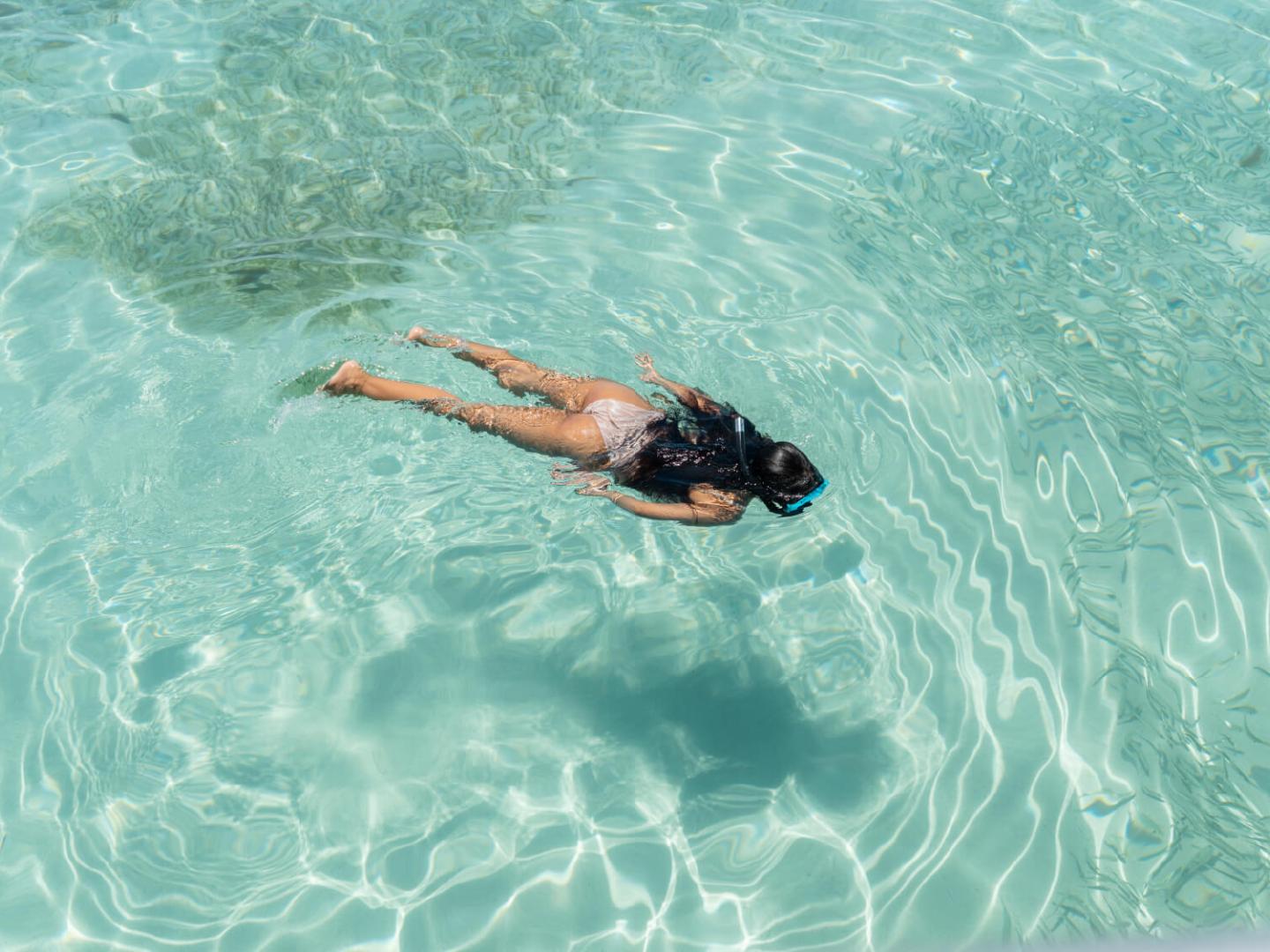 Person snorkeling in clear turquoise water.