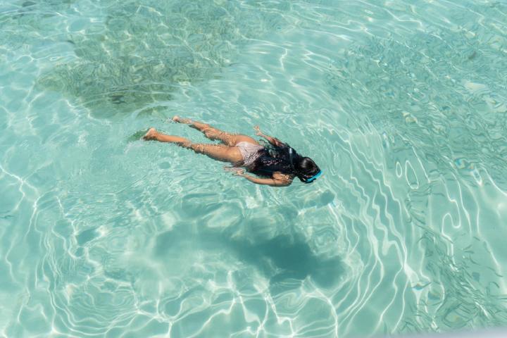 Person snorkeling in clear turquoise water.